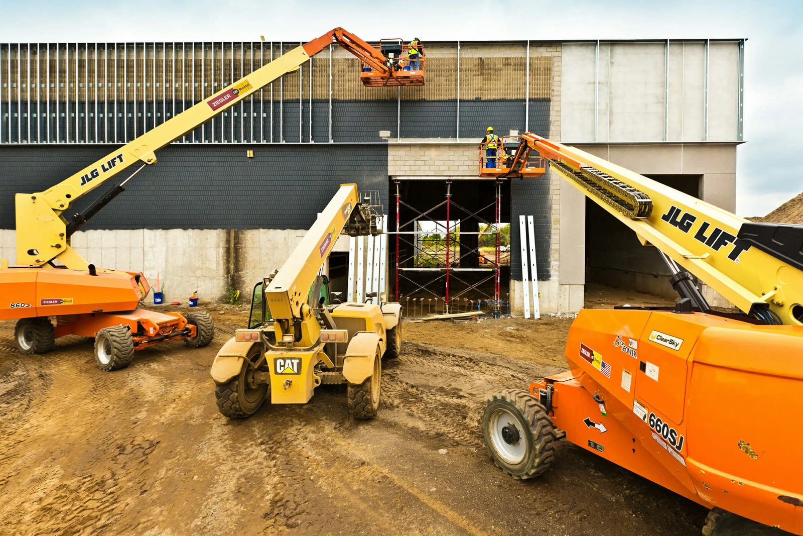Boom lifts and a telehandler working a building site