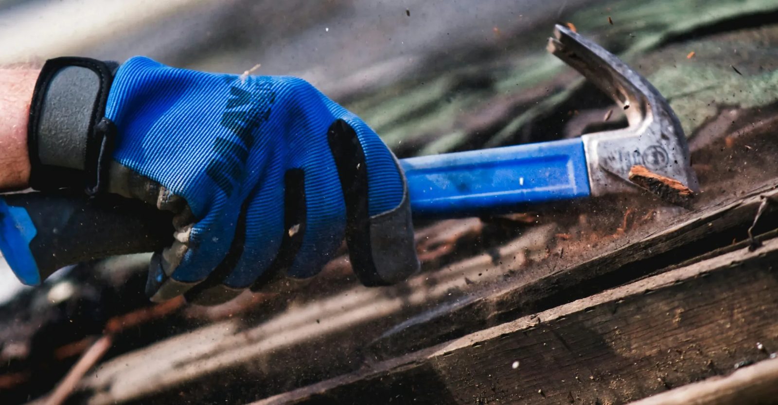 A gloved hand reaching for a hammer on a workbench