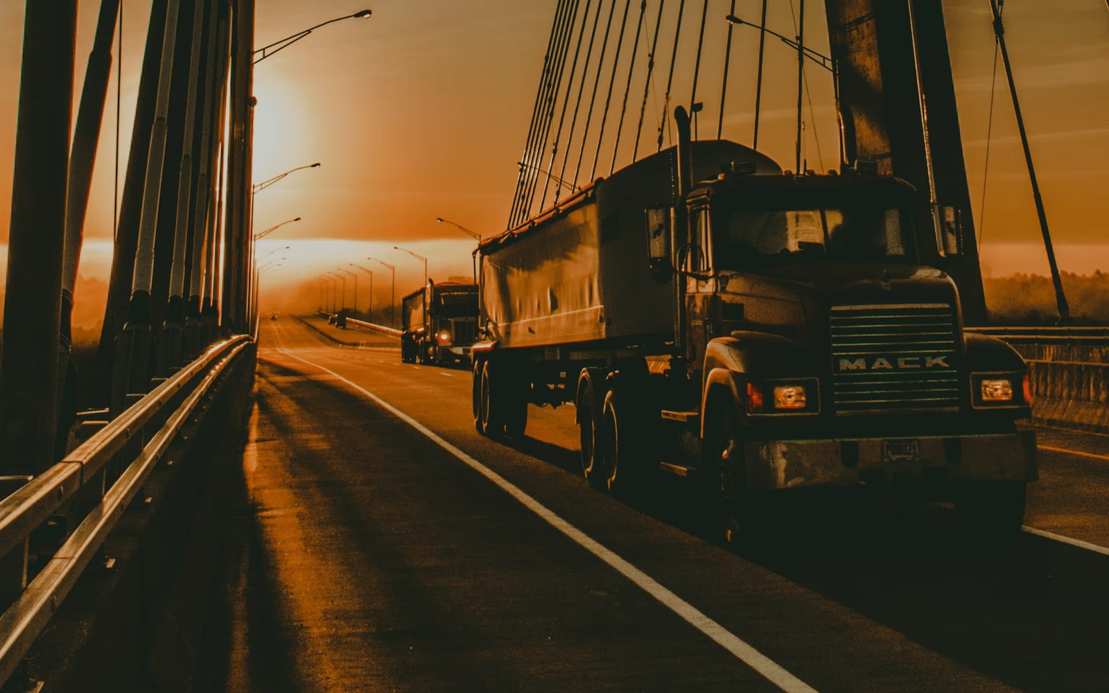 A loaded truck crossing a bridge at sunset