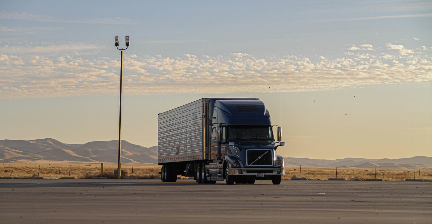 A tractor-trailer on an open highway at dusk